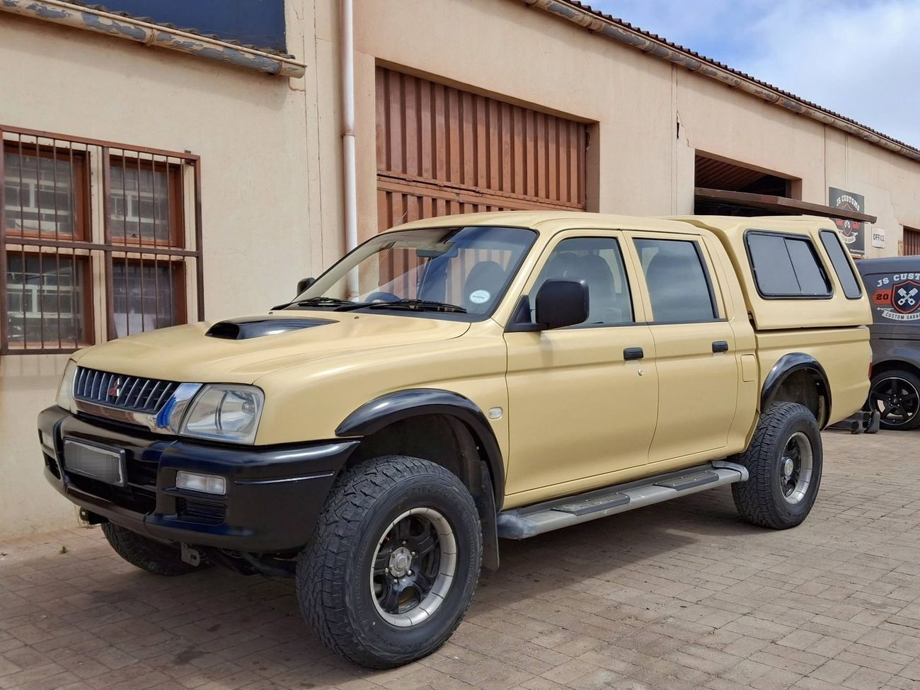 Sand coloured Mitsubishi double cab bakkie with canopy and bonnet scoop